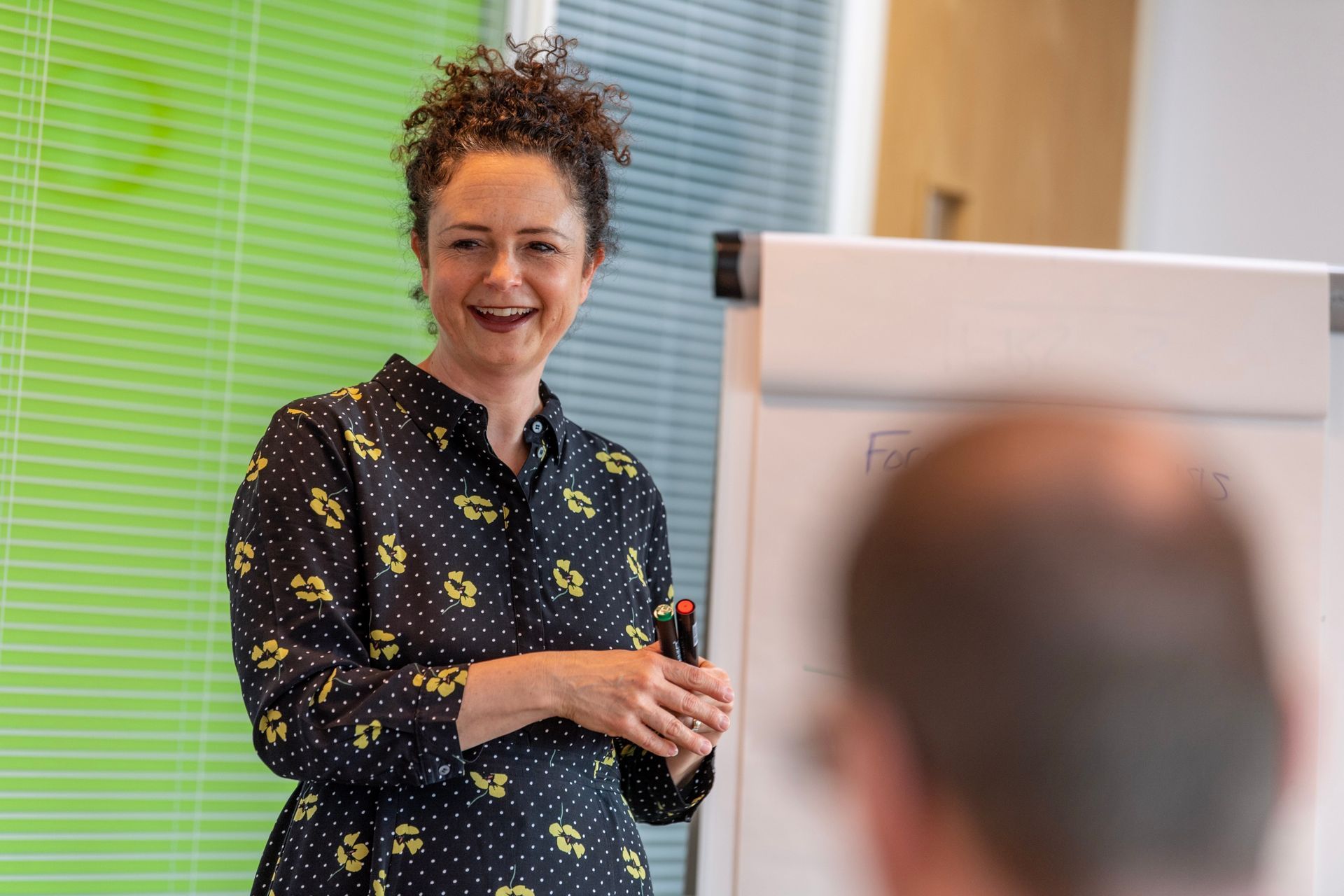 Kay is giving a presentation in front of a flip chart.