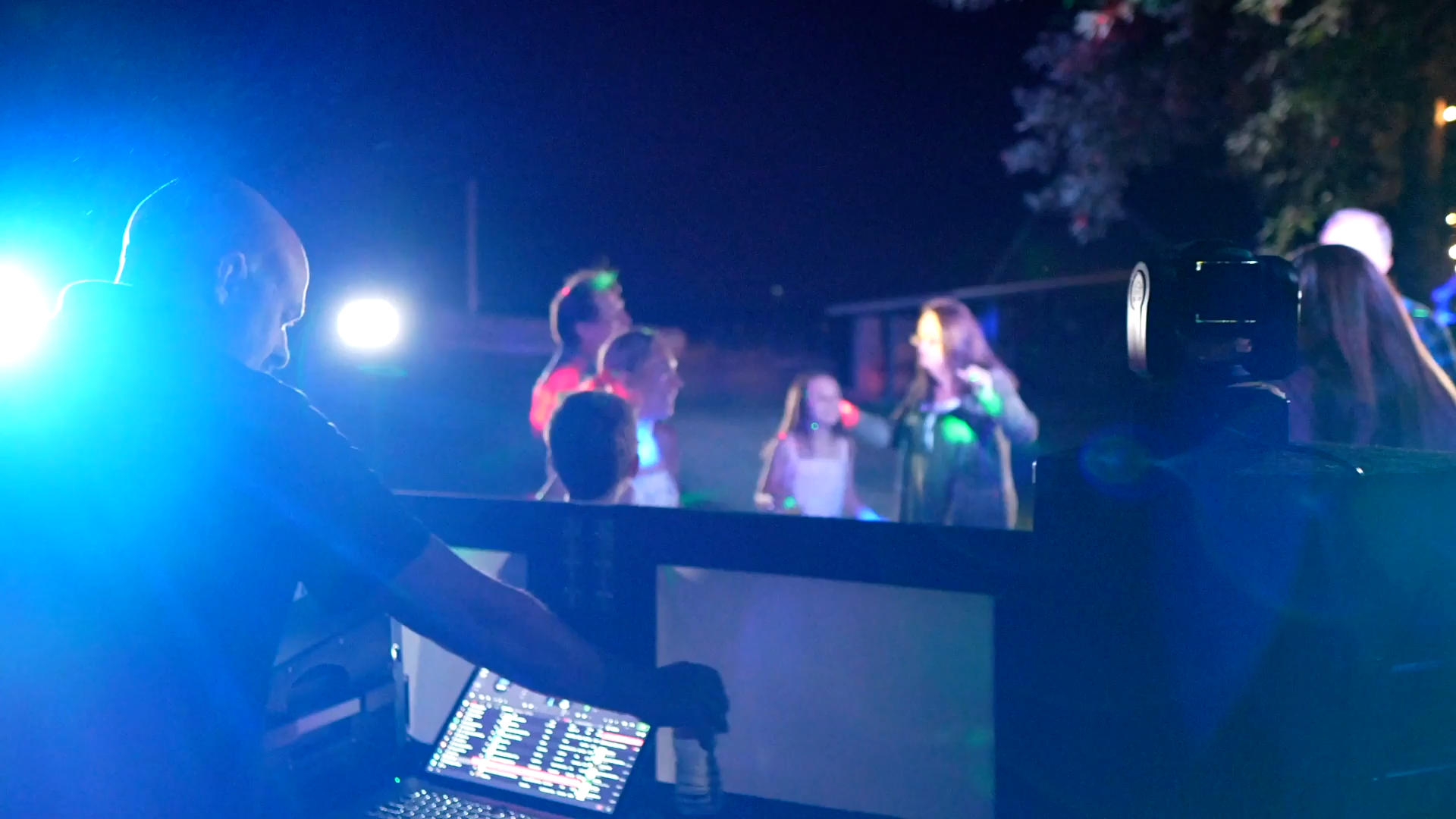 Cloud and Fire DJ at a nighttime party with people dancing under blue and green lights.