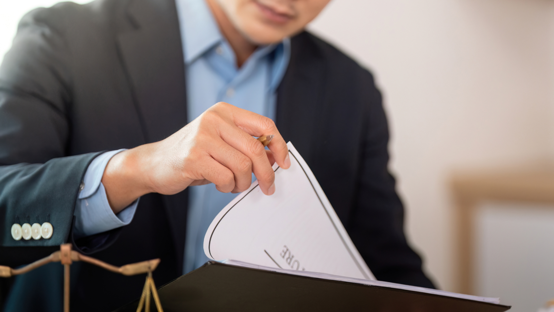 Person in a suit sorts through documents in a file, scales of justice visible.