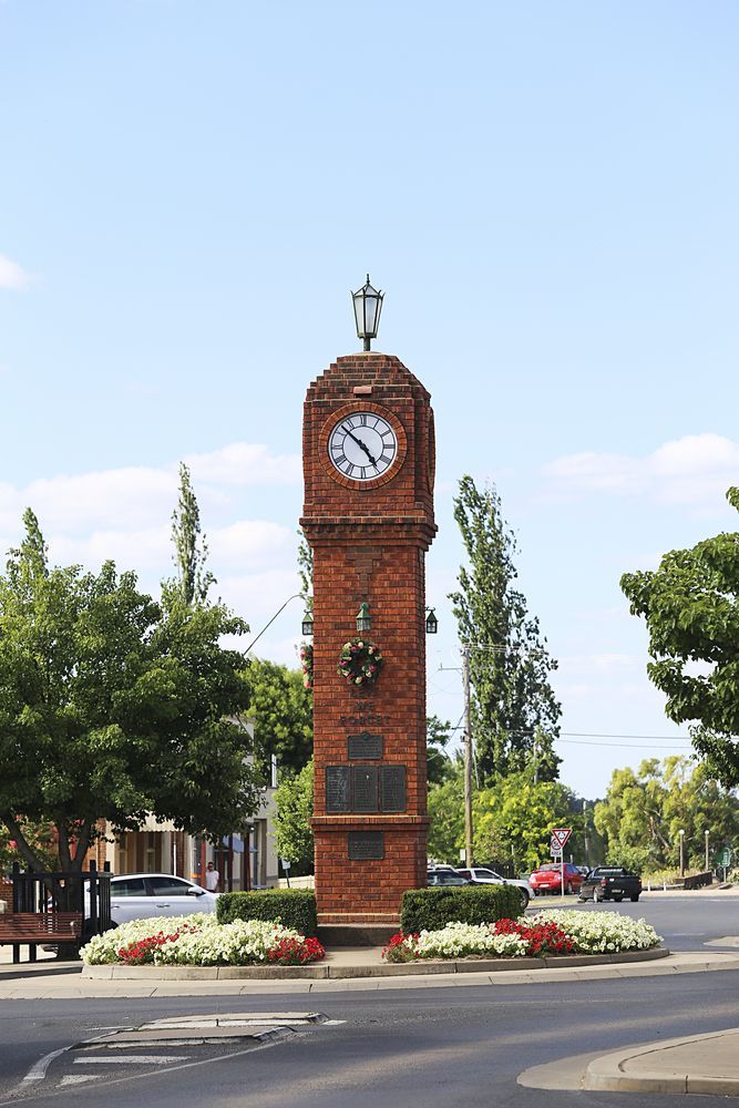 Red Brick Clock Tower in a Roundabout, Surrounded by Green Trees and Flowers — Pure Plumbing & Electrical in Mudgee, NSW