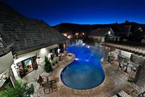 An aerial view of a large swimming pool in the backyard of a house at night.