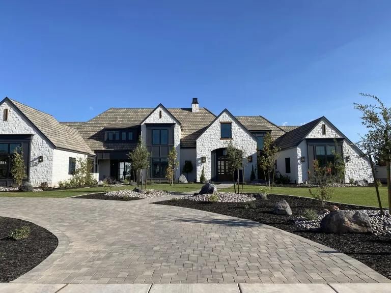 A large white house with a brick driveway in front of it.