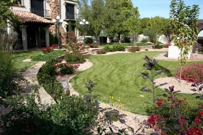 A large house with a lush green lawn and flowers in front of it