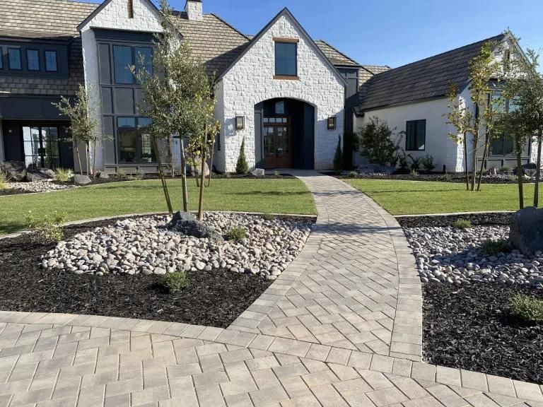 A large white house with a brick walkway leading to it.