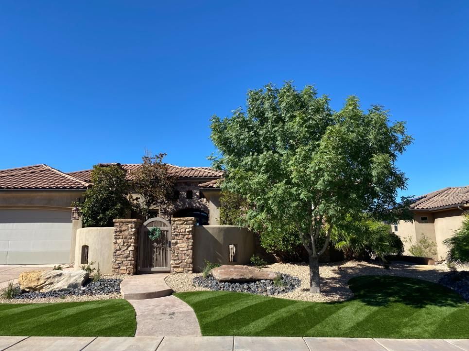 A house with a lush green lawn and a tree in front of it.