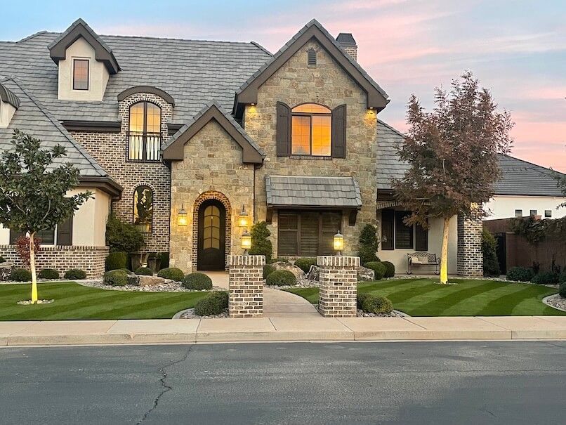 A large house with a lush green lawn is sitting on the side of the road.