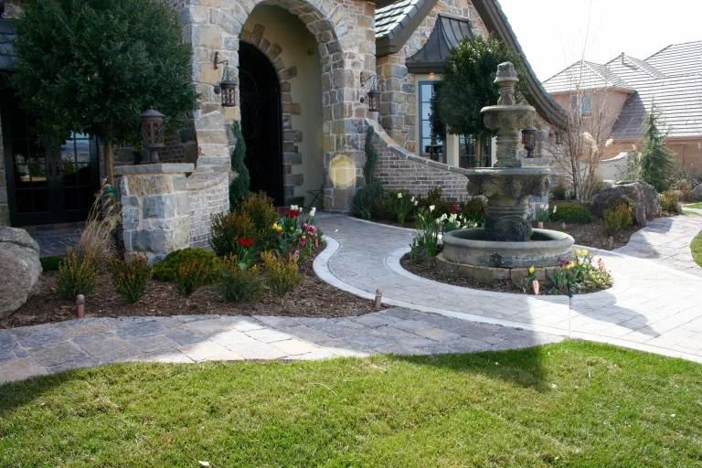 A stone house with a fountain in front of it.