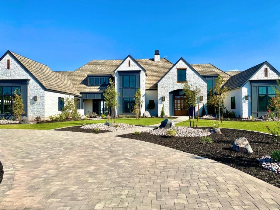 A large white house with a brick driveway in front of it.