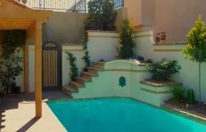 A large swimming pool in the backyard of a house with stairs leading to it.