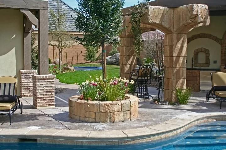 A swimming pool with a stone planter in the middle of it