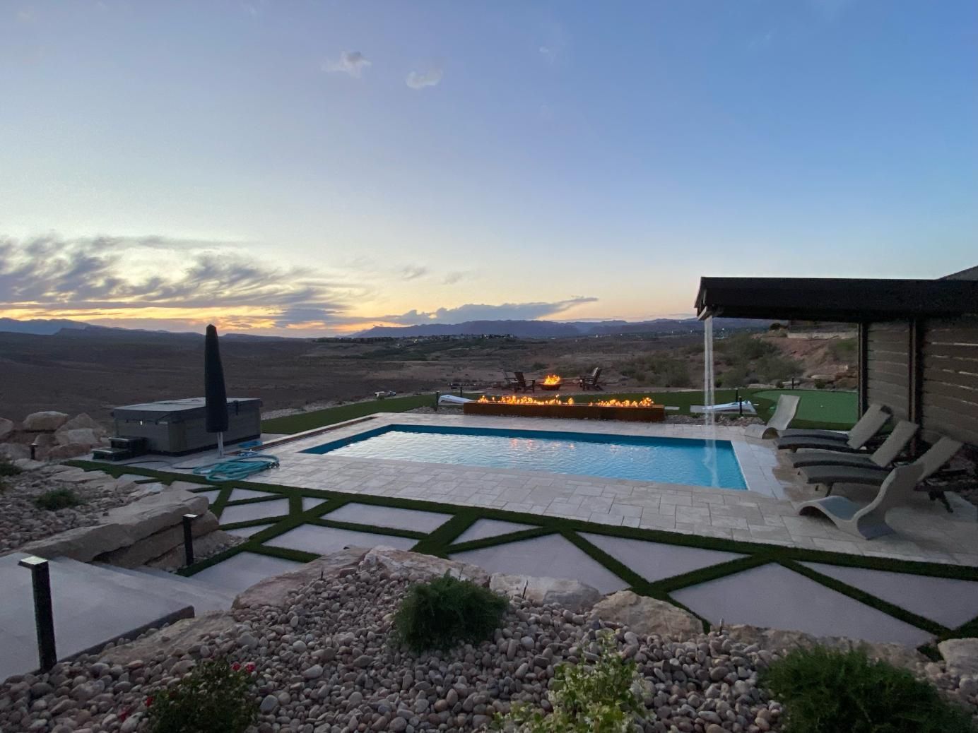 A large swimming pool with a fire pit in the background