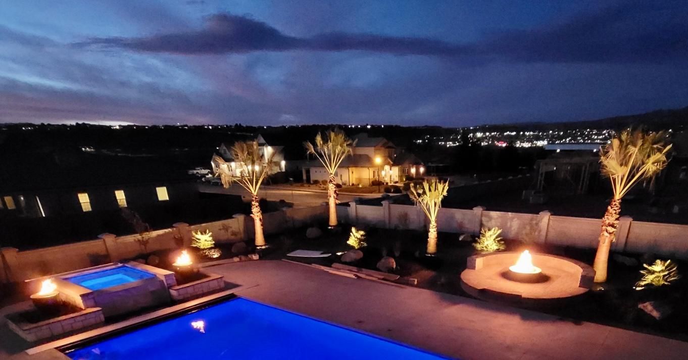 An aerial view of a swimming pool and fire pit at night.