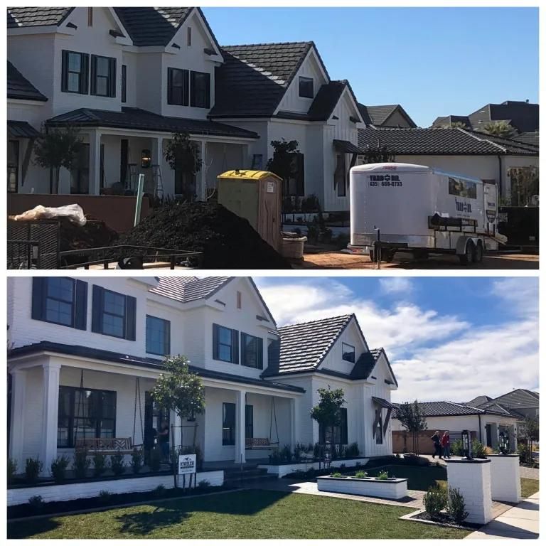 A white trailer is parked in front of a white house