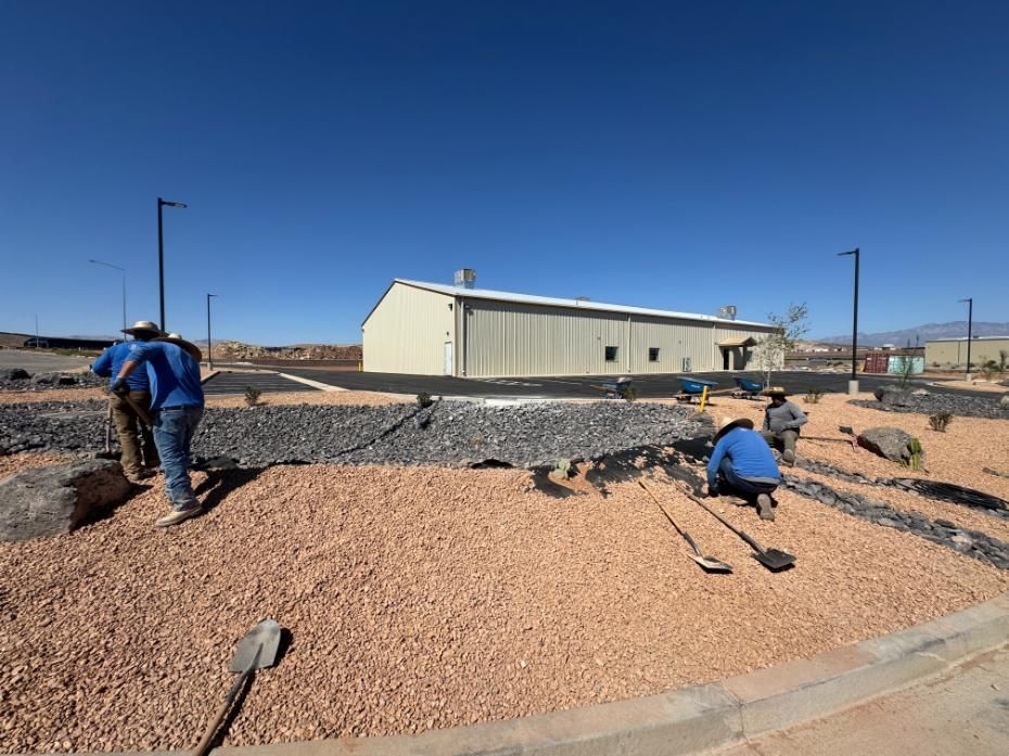 A group of men are working on a gravel road in front of a building.