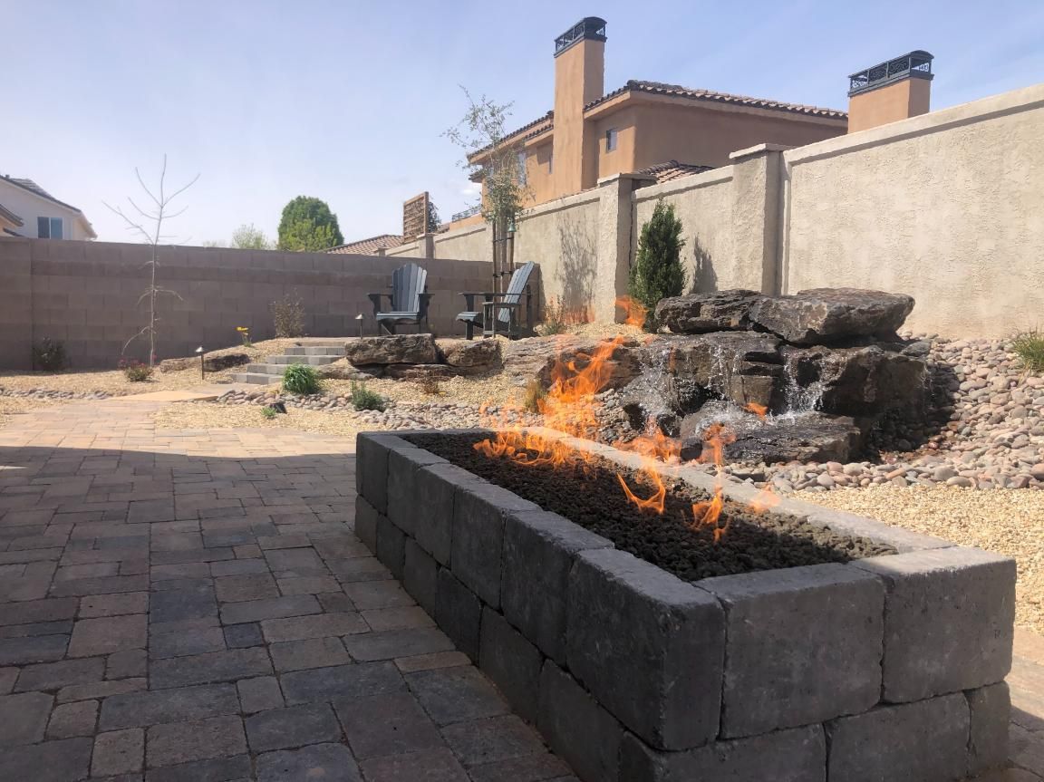 A fire pit with flames coming out of it in a backyard.