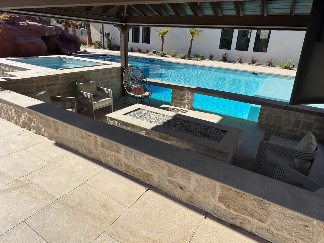 A patio with a fire pit and a swimming pool in the background.