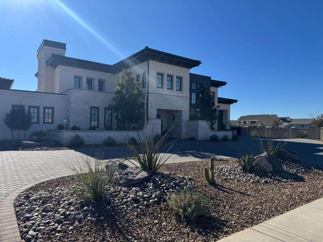 A large white house with a lot of windows is sitting on top of a lush green hillside.