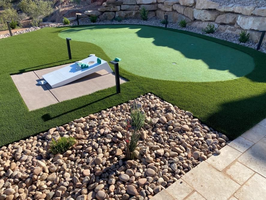 A putting green in a backyard surrounded by rocks