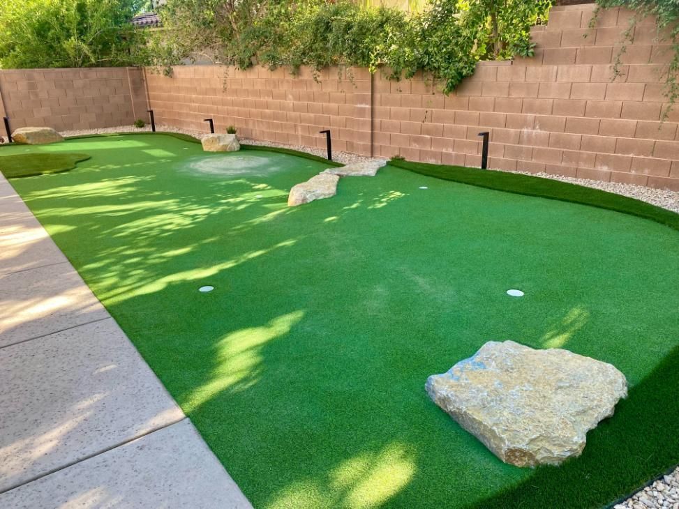 A small golf course in a backyard with a brick wall in the background.