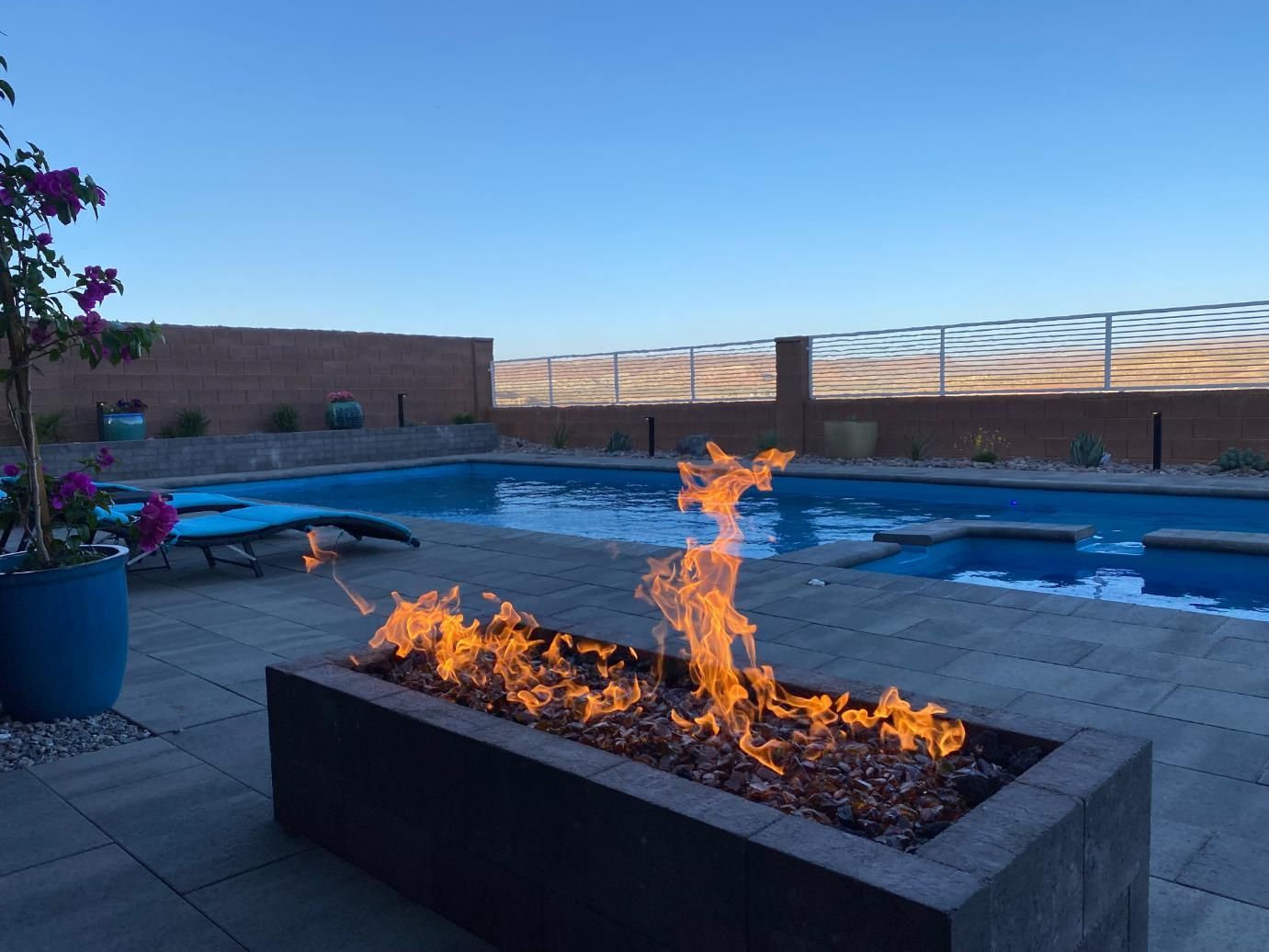 A fire pit in front of a large swimming pool