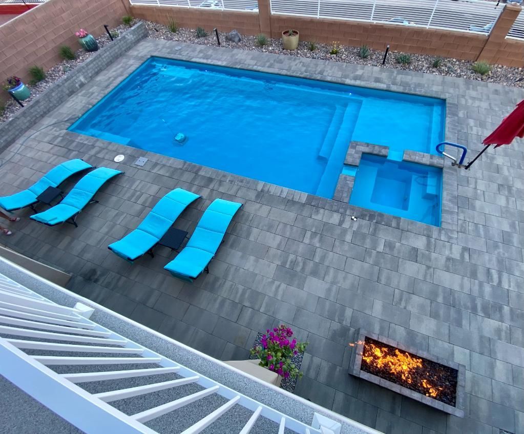 An aerial view of a swimming pool with blue chairs and a fire pit