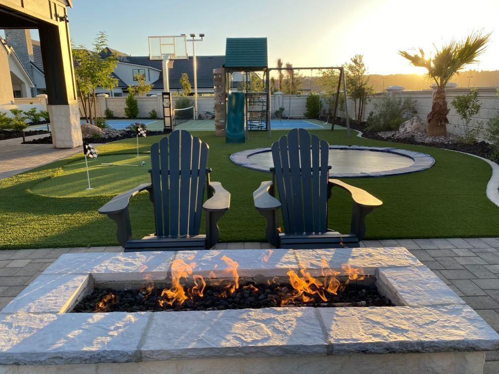 Two lawn chairs are sitting next to a fire pit in a backyard.