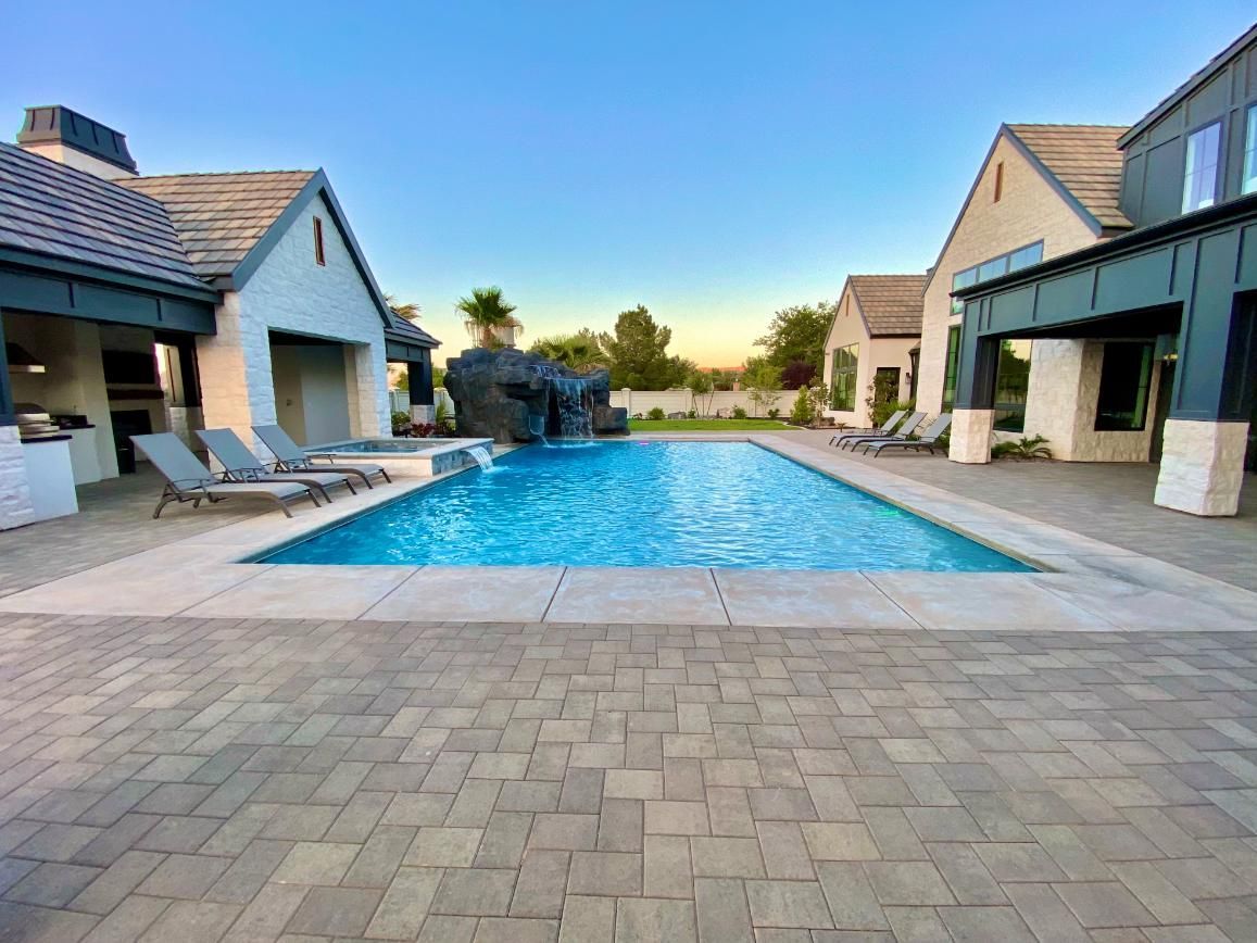 A large swimming pool is surrounded by houses and chairs.