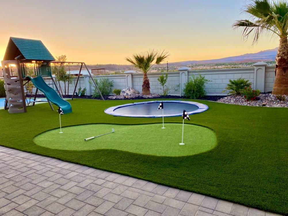A backyard with a putting green and a trampoline.