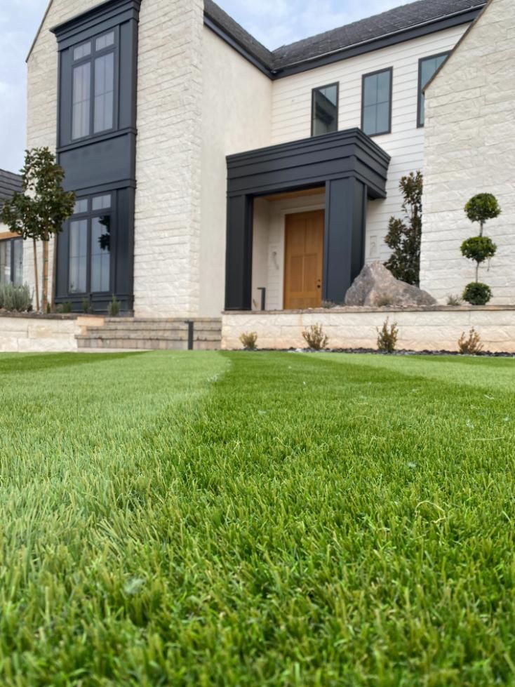 A large white house with a green lawn in front of it.