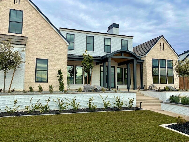 A large white brick house with a large lawn in front of it.