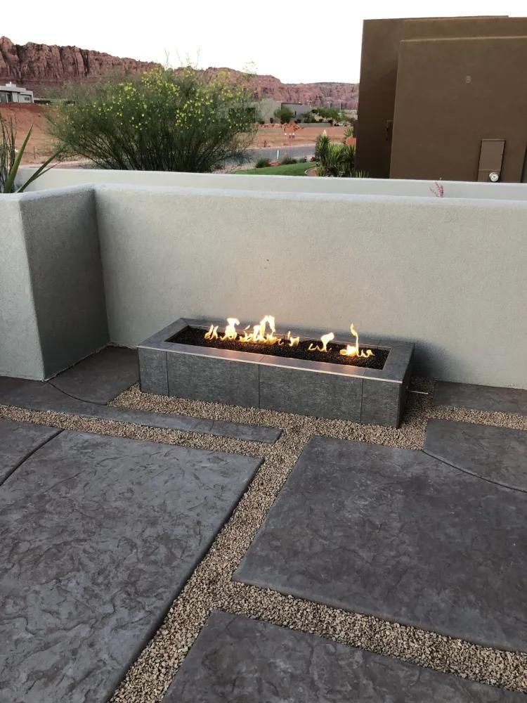 A fire pit is sitting on a patio next to a wall.