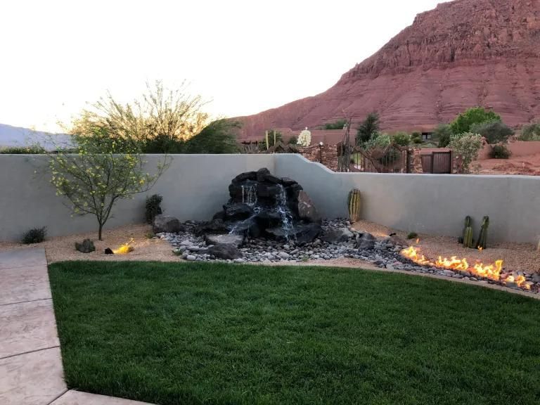 A backyard with a waterfall and a fire pit