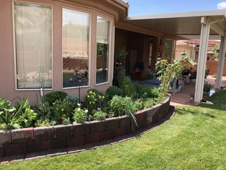 A house with a lot of plants in front of it.