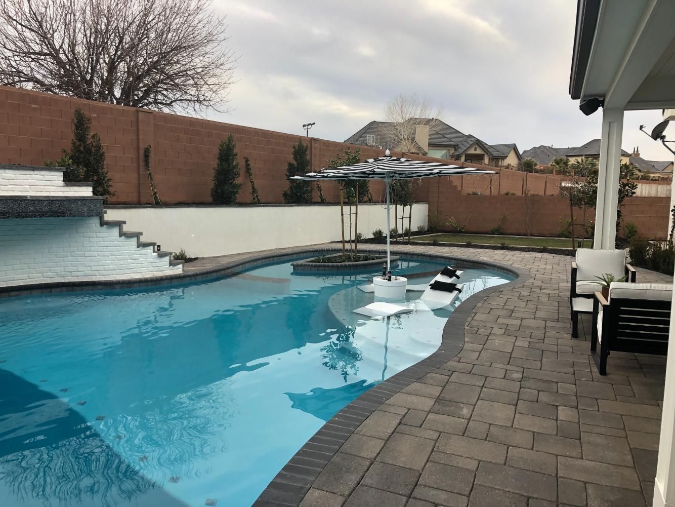 There is a large swimming pool in the backyard of a house.