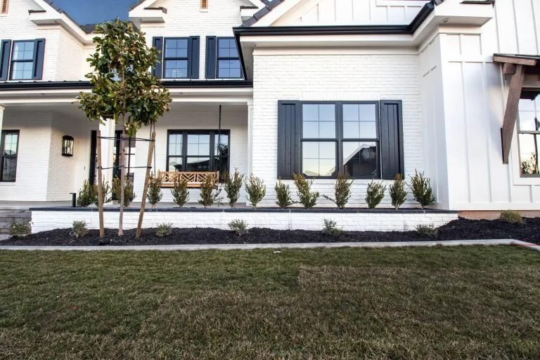 A white house with black shutters and a lush green lawn