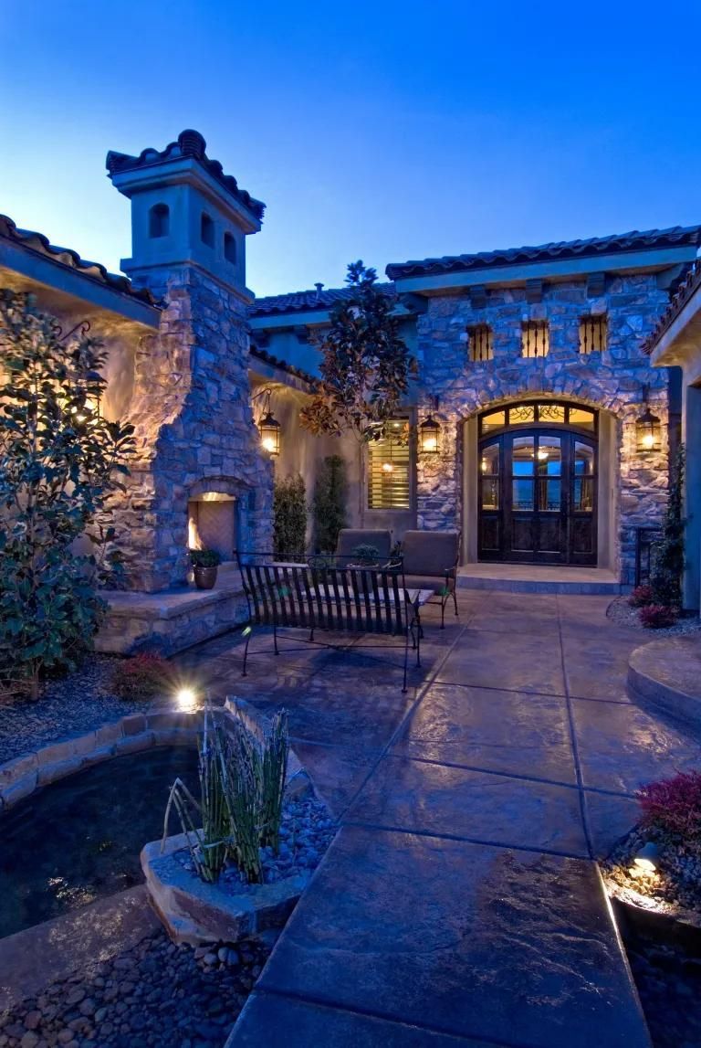 A large stone house with a fountain in front of it at night.