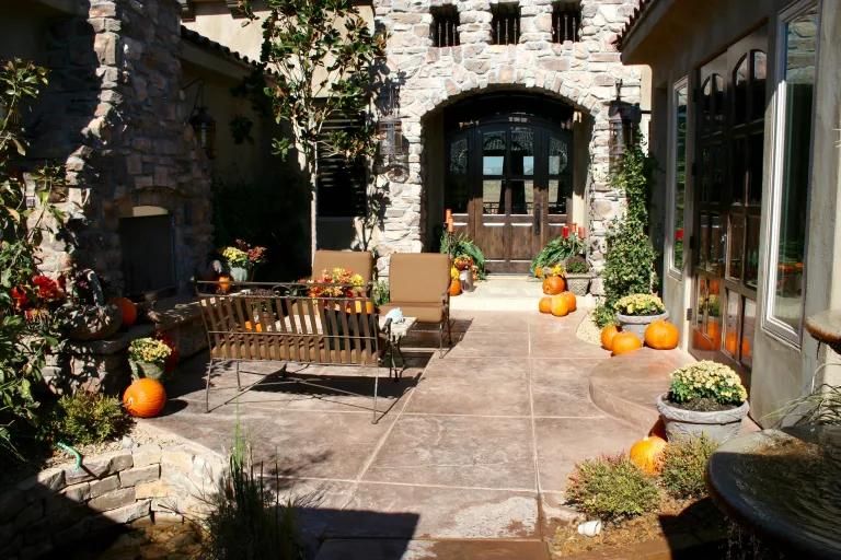 A patio decorated for fall with pumpkins and flowers