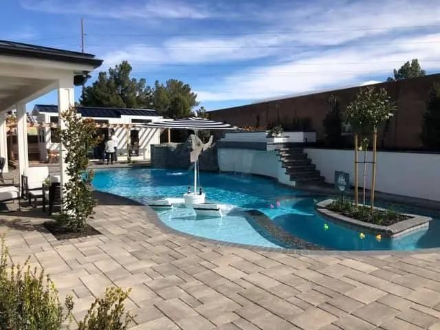 There is a large swimming pool in the backyard of a house.