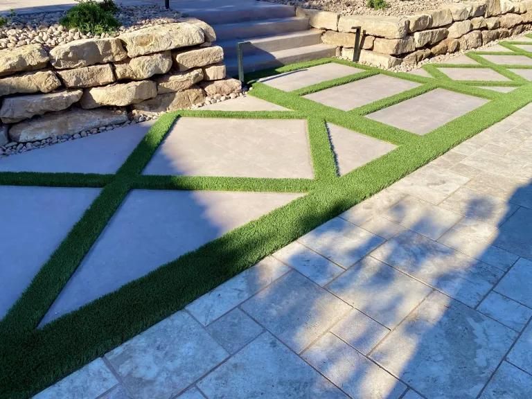 A patio with a stone wall and steps and grass