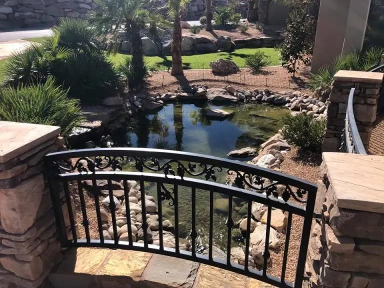 A wrought iron bridge over a pond in a garden