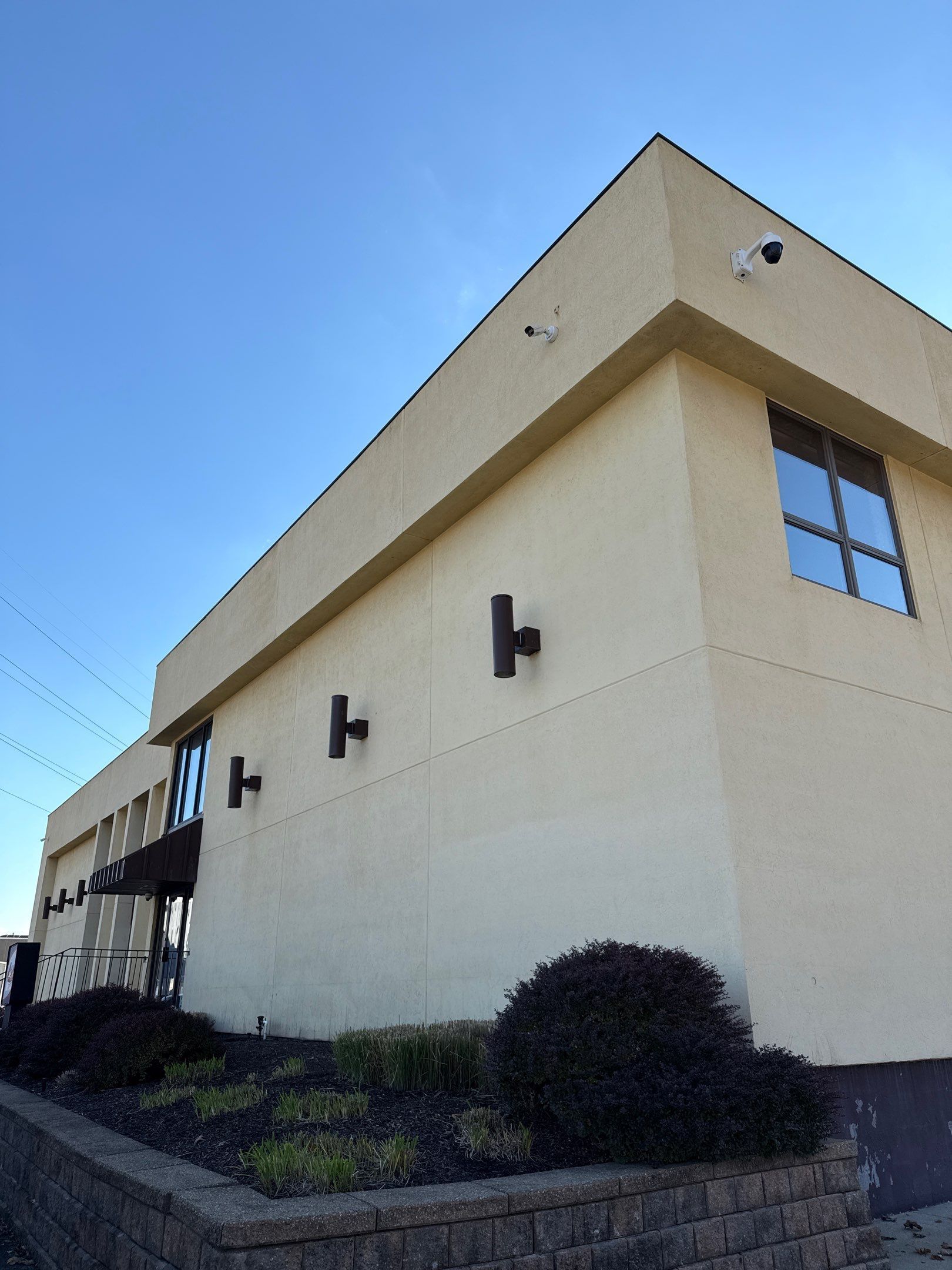 freshly cleaned tan beige building with blue windows against a clear blue sky