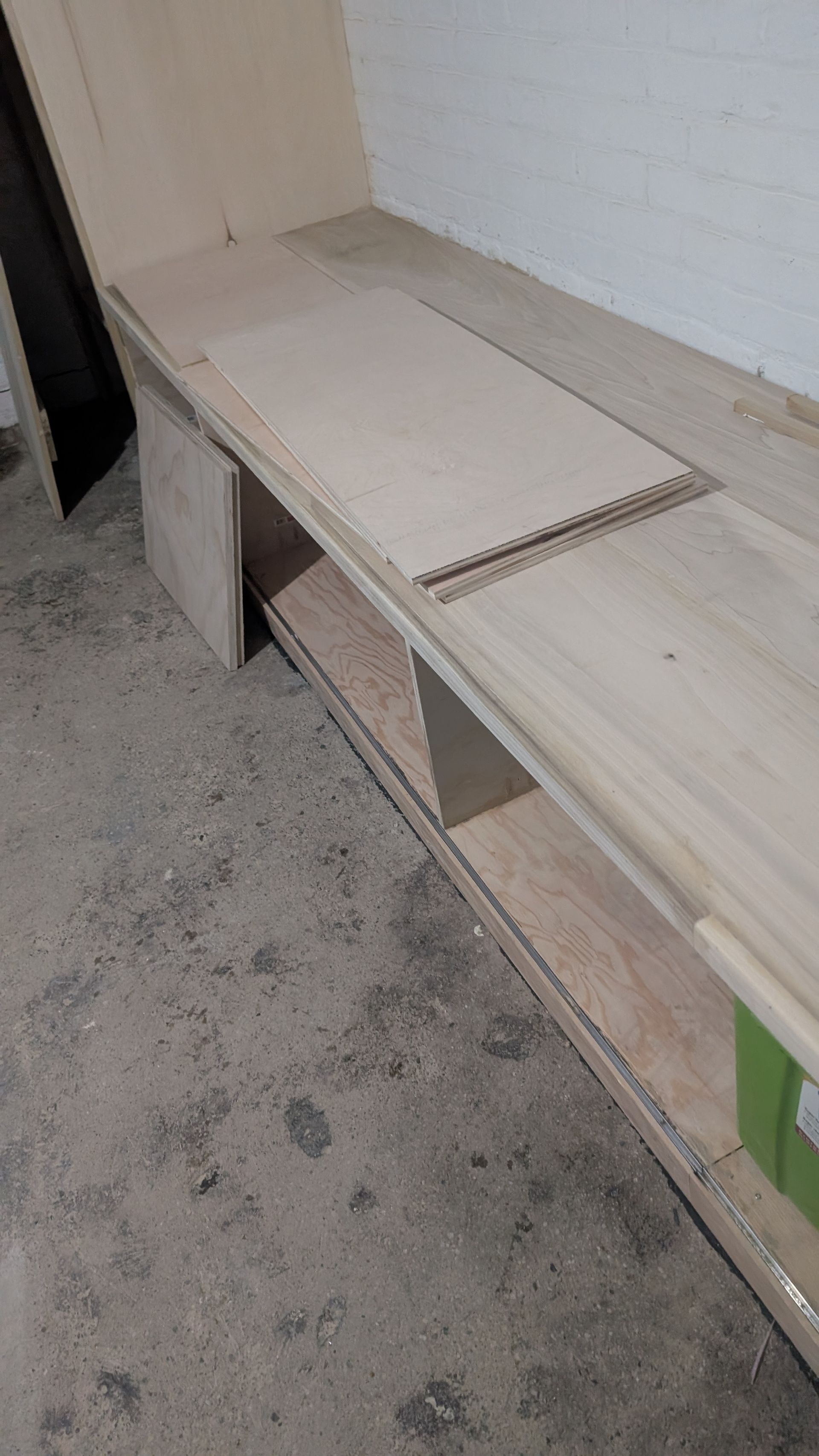 Wooden shelf under construction in a room. Plywood pieces on top.