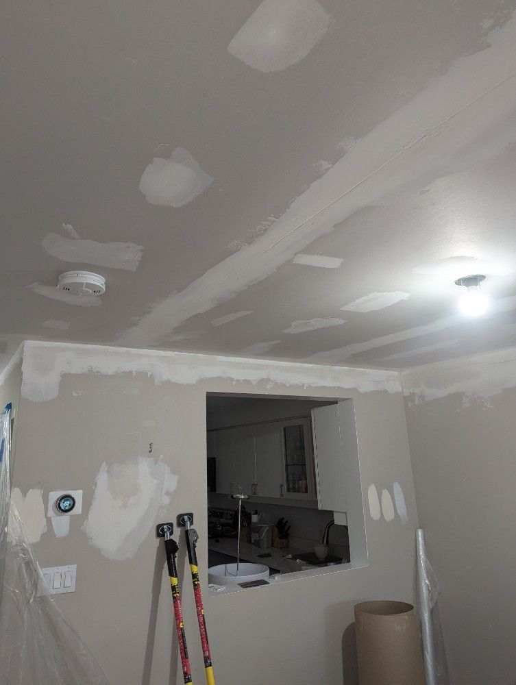 Ceiling and wall under construction, with drywall mud applied. A window in the middle.