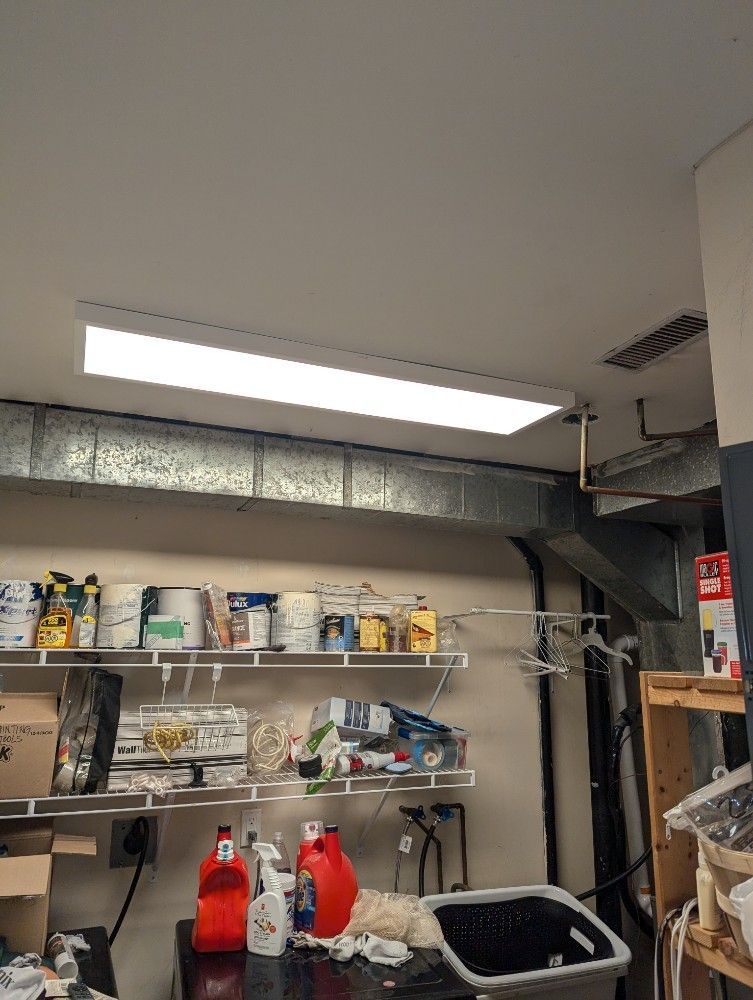 Garage interior with fluorescent ceiling light, shelf of supplies, and laundry items.