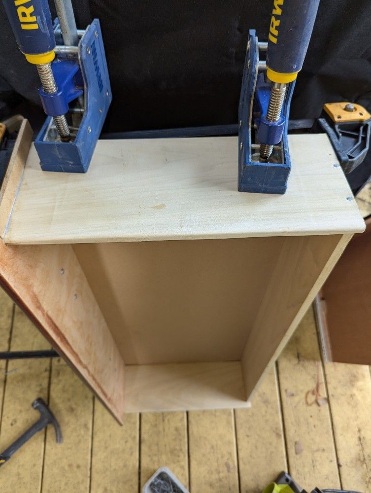 Wooden drawer being assembled with clamps.