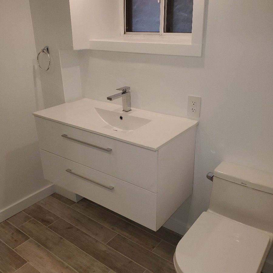 White bathroom sink with two drawers, chrome faucet, and toilet.