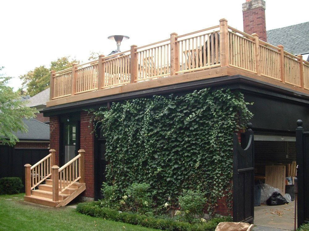 A wooden deck on top of a brick building covered in ivy. A set of stairs leads to the deck.