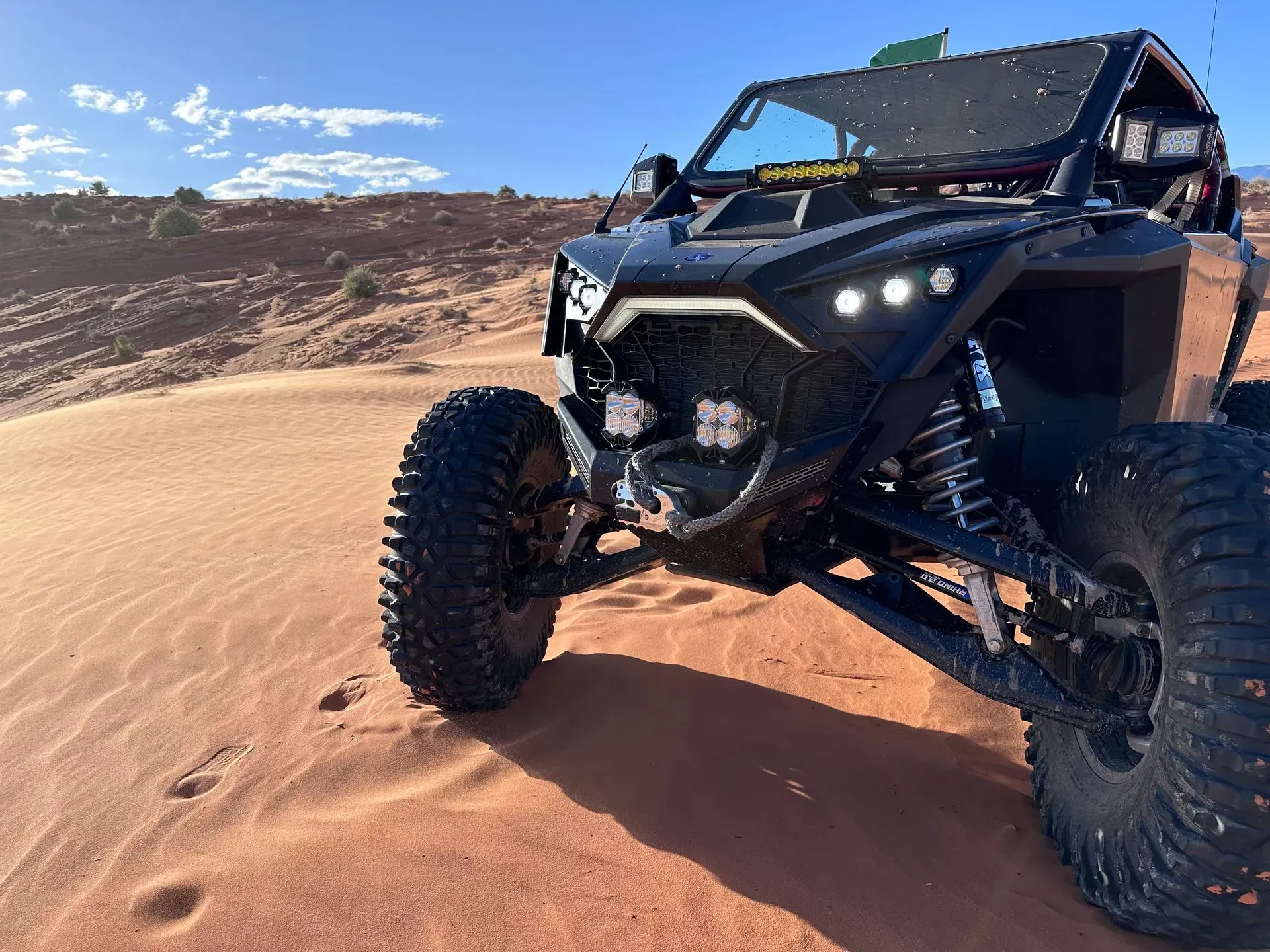 Black off-road buggy driving on sandy desert dunes under a blue sky