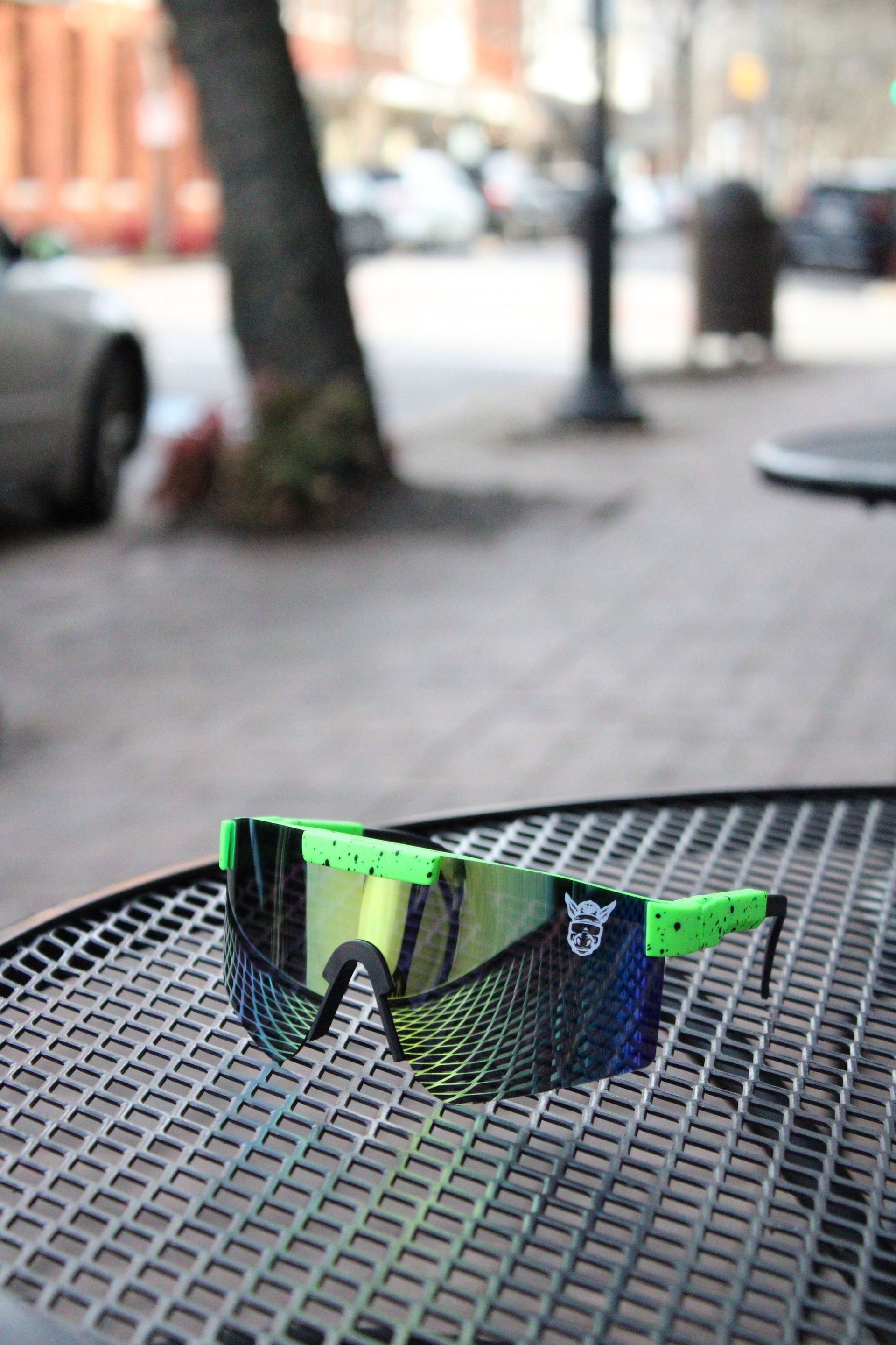 A pair of green and black sunglasses are sitting on a metal table.