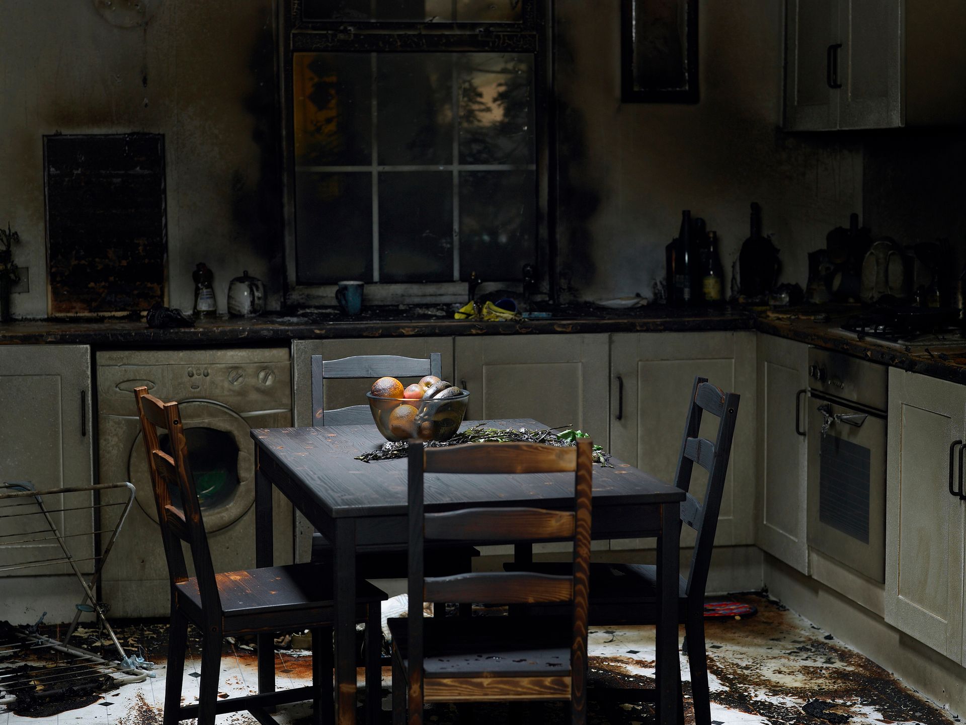 A kitchen with a table and chairs that has been damaged by a fire.